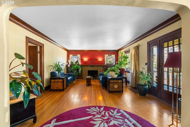 living room with crown molding, wood-type flooring, and a fireplace