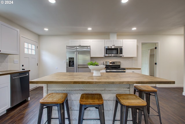 kitchen with butcher block counters, a kitchen breakfast bar, white cabinets, and appliances with stainless steel finishes