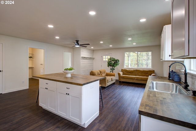 kitchen featuring dark hardwood / wood-style flooring, a center island, white cabinets, sink, and a kitchen breakfast bar