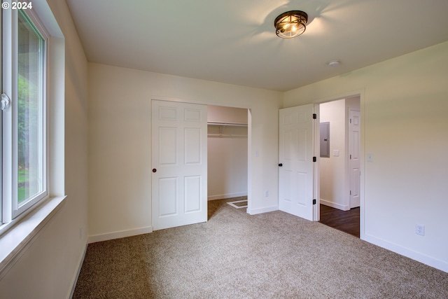 unfurnished bedroom featuring electric panel, dark colored carpet, and a closet