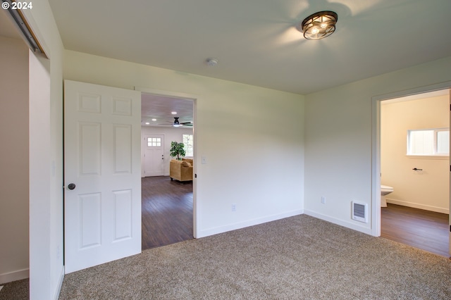 unfurnished bedroom with dark wood-type flooring and connected bathroom