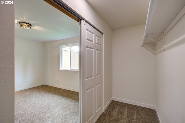 walk in closet featuring dark colored carpet