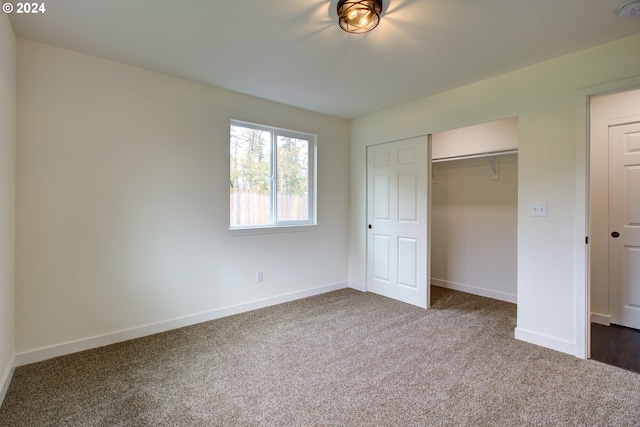 unfurnished bedroom with dark colored carpet and a closet