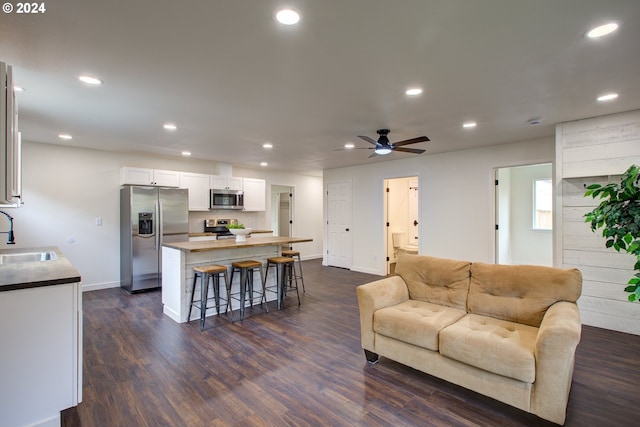 living room featuring dark wood-type flooring, sink, and ceiling fan