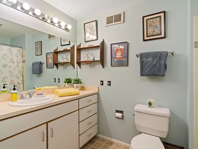 bathroom with toilet, vanity with extensive cabinet space, and tile floors