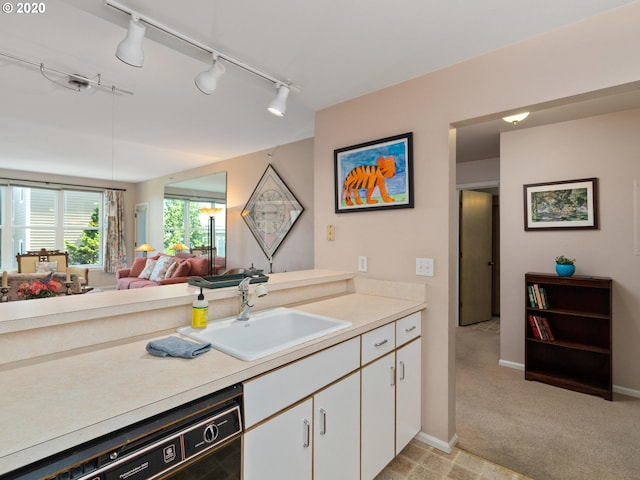 kitchen featuring light colored carpet, sink, rail lighting, white cabinets, and black dishwasher