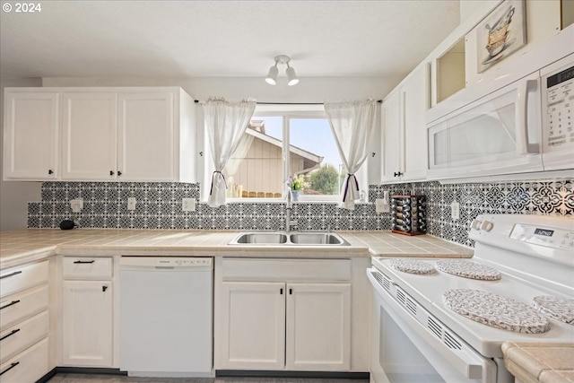 kitchen featuring sink, white appliances, and white cabinetry