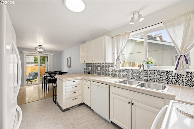 kitchen featuring kitchen peninsula, sink, white appliances, and white cabinets