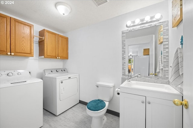 clothes washing area featuring light hardwood / wood-style flooring, sink, a textured ceiling, and washer and dryer