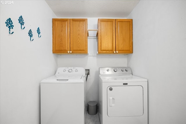 clothes washing area with a textured ceiling, independent washer and dryer, and cabinets