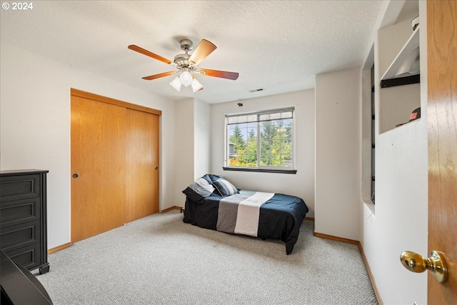 carpeted bedroom featuring a textured ceiling, ceiling fan, and a closet