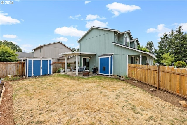 rear view of property featuring a yard, a patio, and a shed