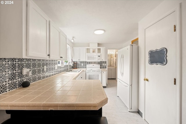 kitchen featuring white cabinets, white appliances, kitchen peninsula, tile counters, and tasteful backsplash