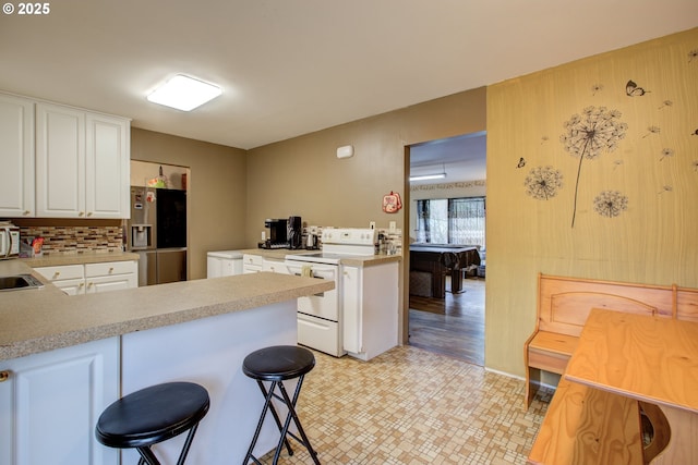 kitchen featuring white cabinetry, stainless steel refrigerator with ice dispenser, white range with electric stovetop, kitchen peninsula, and decorative backsplash