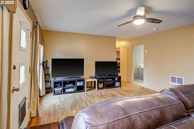 living room featuring heating unit, light hardwood / wood-style flooring, and ceiling fan