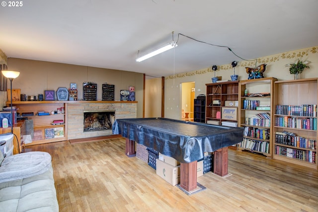 game room featuring a stone fireplace, hardwood / wood-style floors, and pool table