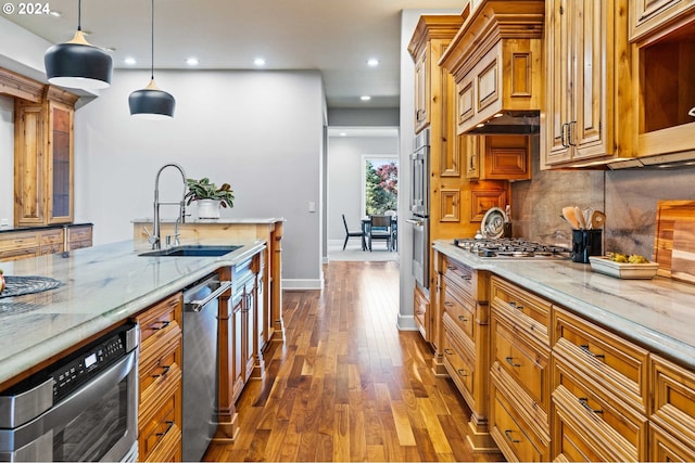 kitchen featuring decorative light fixtures, light stone counters, dark hardwood / wood-style floors, backsplash, and sink