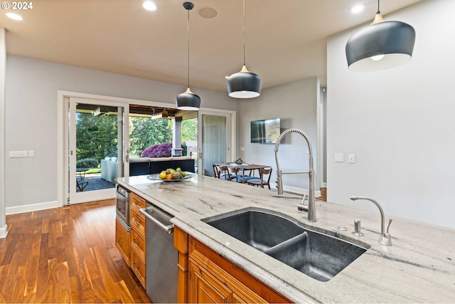 kitchen with light stone countertops, dishwasher, hardwood / wood-style flooring, and pendant lighting