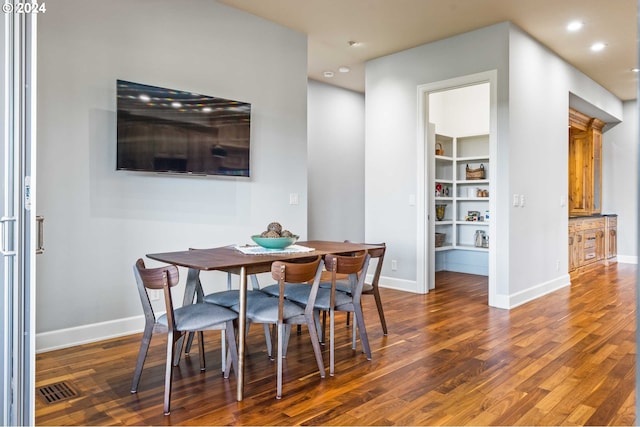 dining space featuring dark wood-type flooring and built in features