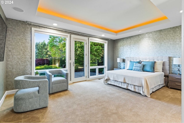 carpeted bedroom featuring access to exterior and a raised ceiling