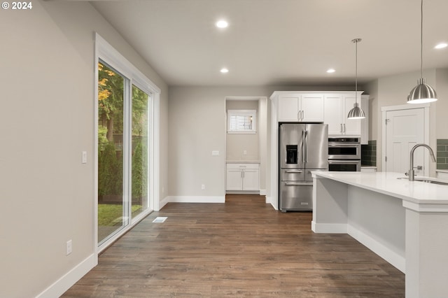 kitchen with sink, dark wood-type flooring, decorative light fixtures, white cabinets, and appliances with stainless steel finishes