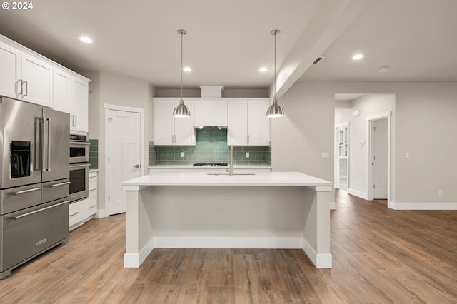 kitchen with pendant lighting, white cabinets, a center island with sink, light hardwood / wood-style flooring, and appliances with stainless steel finishes