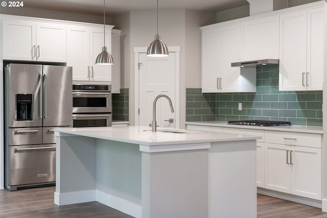 kitchen with white cabinets, wood-type flooring, a kitchen island with sink, and appliances with stainless steel finishes