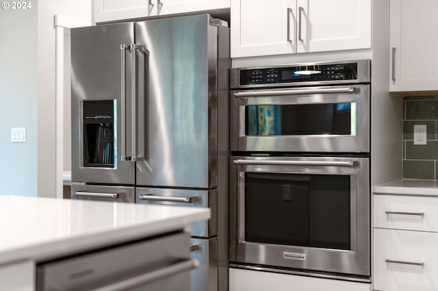 kitchen with white cabinets, appliances with stainless steel finishes, and decorative backsplash