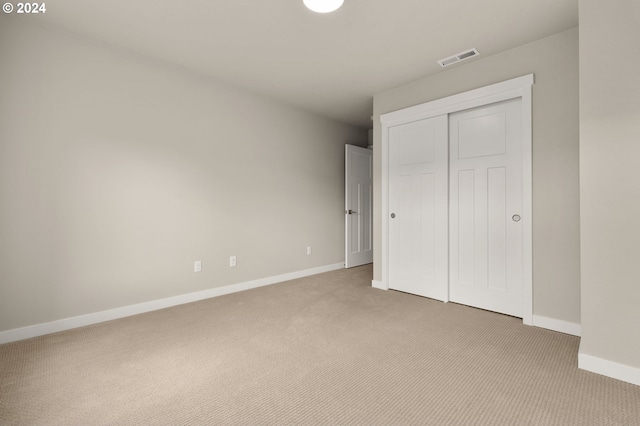 unfurnished bedroom featuring light colored carpet and a closet