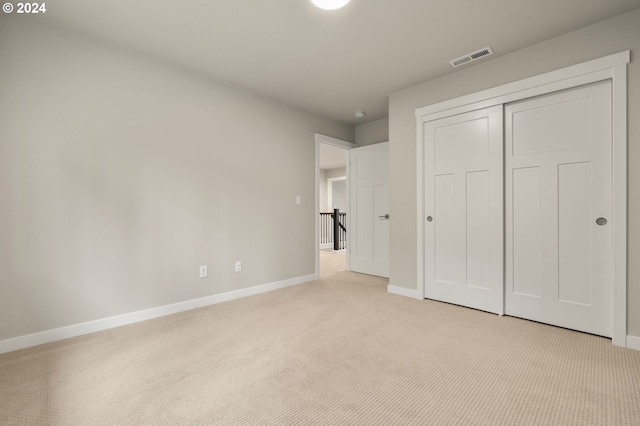 unfurnished bedroom with a closet and light colored carpet