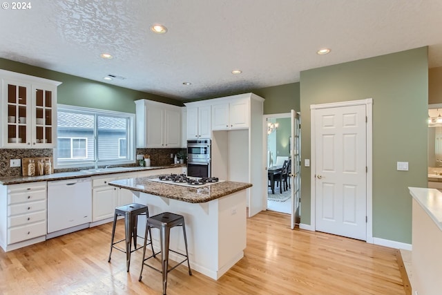 kitchen with white cabinets, light hardwood / wood-style floors, white appliances, and a kitchen island