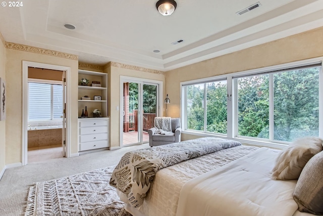 carpeted bedroom with a tray ceiling and access to exterior