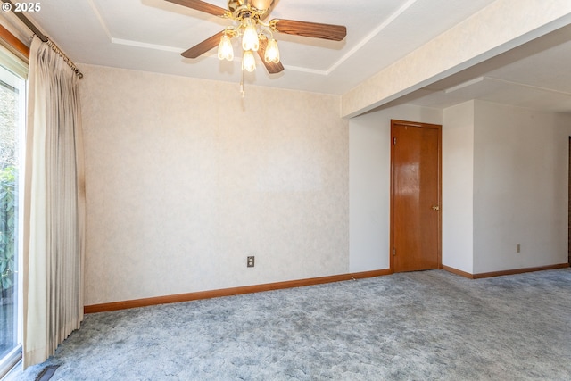 unfurnished room featuring a ceiling fan, a tray ceiling, carpet flooring, and baseboards