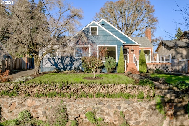 view of front of property with a wooden deck and a front lawn