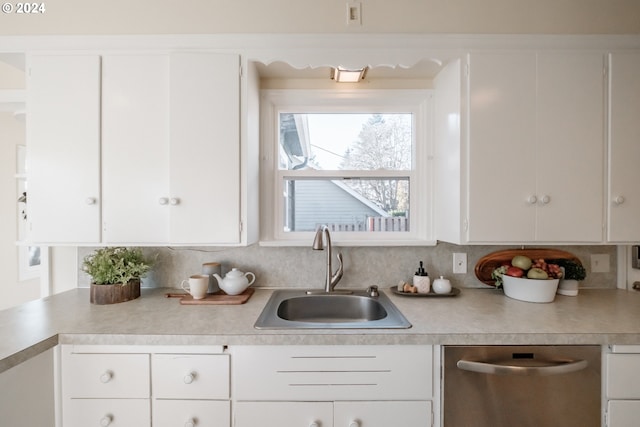 kitchen with dishwasher, white cabinetry, sink, and tasteful backsplash