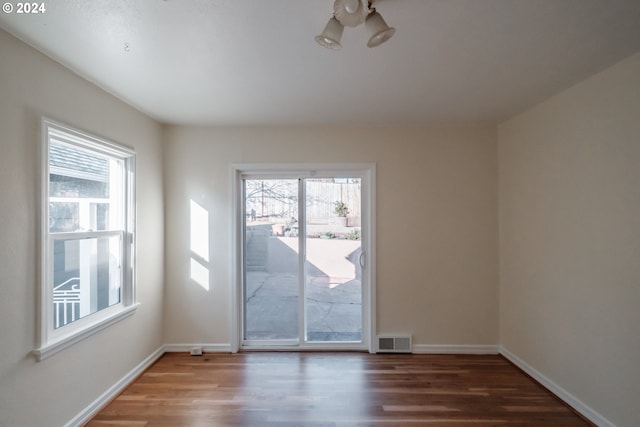 unfurnished room featuring a healthy amount of sunlight and dark hardwood / wood-style flooring