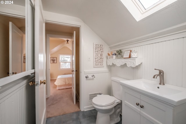 bathroom featuring tile patterned flooring, vanity, toilet, and vaulted ceiling with skylight