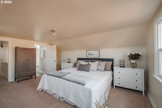 bedroom with ensuite bathroom, light colored carpet, and multiple windows