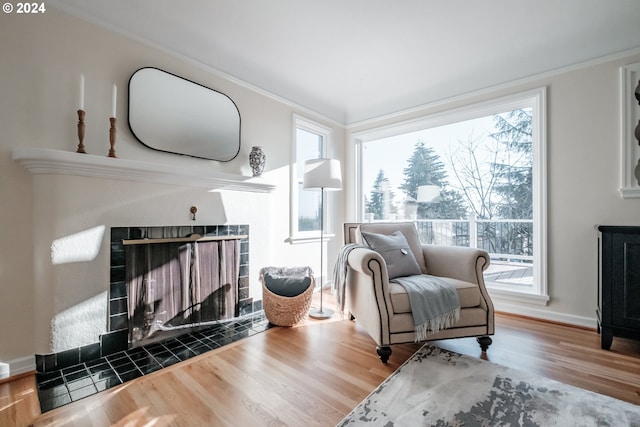 sitting room with hardwood / wood-style floors, crown molding, and a tiled fireplace