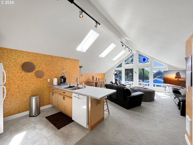 kitchen featuring sink, a kitchen breakfast bar, white appliances, track lighting, and vaulted ceiling with skylight