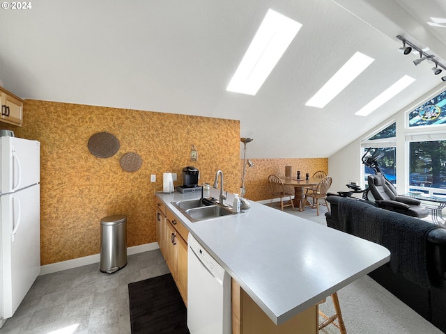 kitchen with kitchen peninsula, white appliances, lofted ceiling, and sink