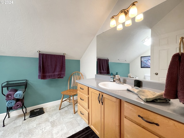 bathroom with a textured ceiling, vanity, and vaulted ceiling