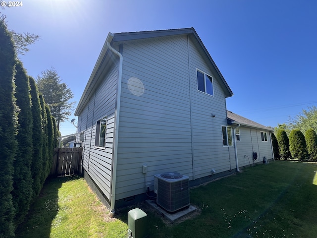 view of property exterior with a lawn and central AC