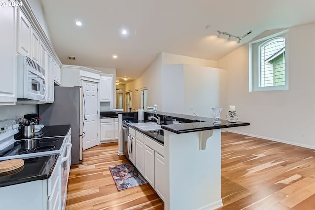 kitchen featuring white appliances, light wood-type flooring, a kitchen bar, white cabinetry, and rail lighting