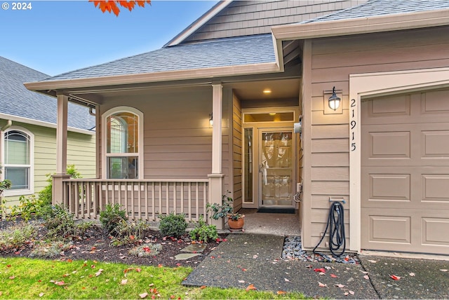 entrance to property featuring covered porch and a garage