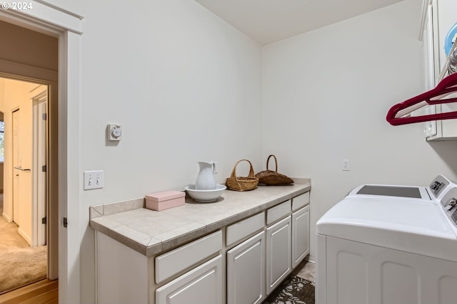 laundry area with independent washer and dryer, wood-type flooring, and cabinets