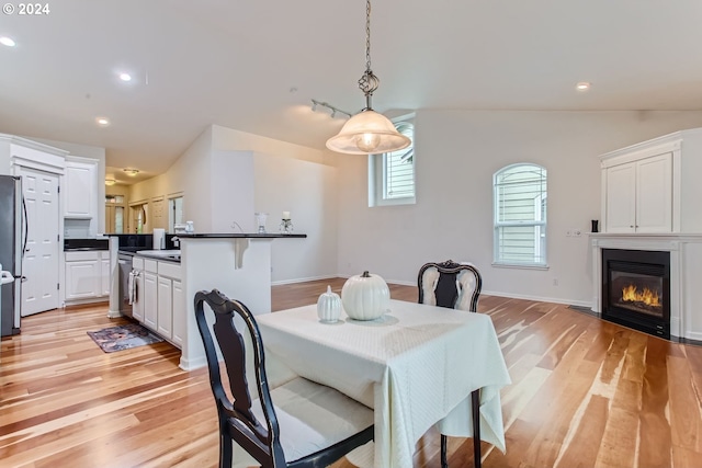 dining space featuring lofted ceiling and light hardwood / wood-style flooring