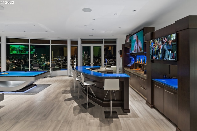 kitchen featuring a center island, a breakfast bar area, dark brown cabinets, billiards, and light tile floors