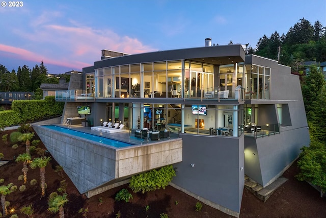 back house at dusk featuring a balcony