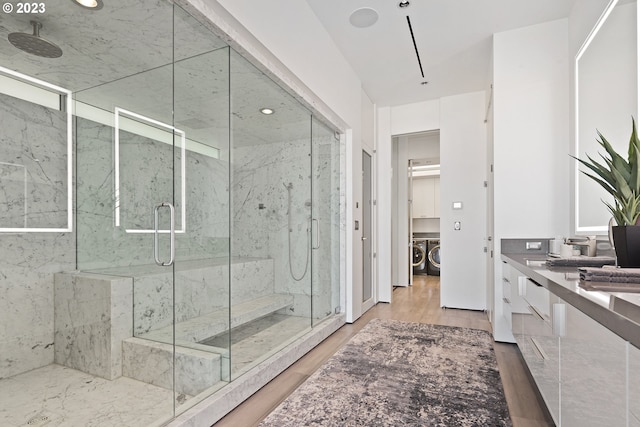 bathroom with washing machine and dryer, an enclosed shower, hardwood / wood-style flooring, and vanity